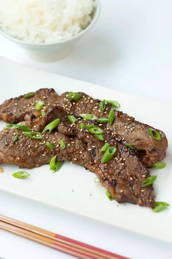 LA galbi Korean BBQ short ribs in a kiwi, garlic and soy sauce based kalbi marinade, grilled and garnished with green onions and black pepper.