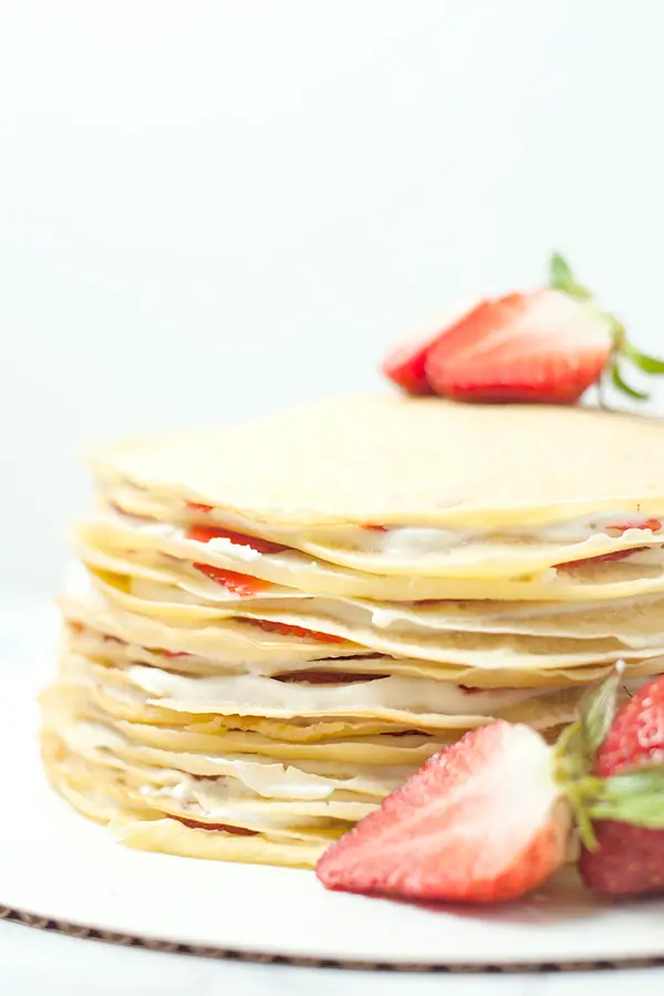 Finished product of strawberry crepe cake topped with a strawberry.