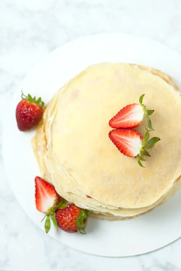 top view of whole layered Japanese crepe cake garnished with strawberry. 