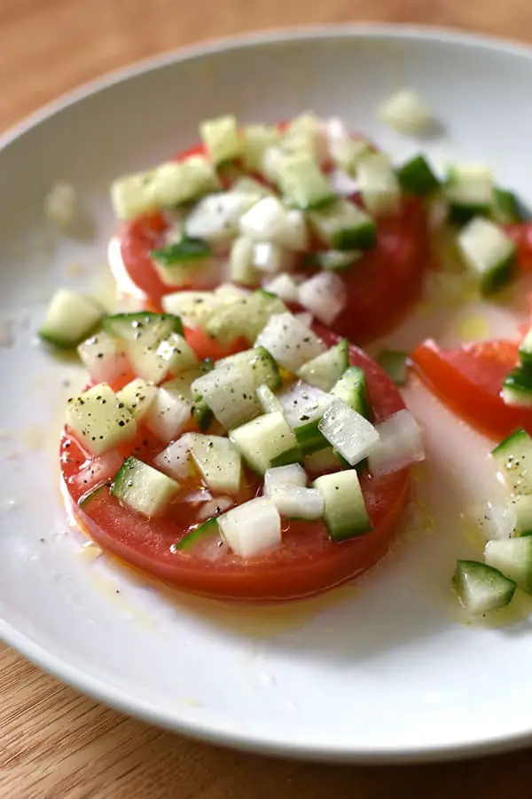 Sliced Tomato Salad with Cucumber Onion Marinade- Sliced tomatoes topped with a chopped cucumbers and onion in a tangy marinade. This sliced tomato salad is so fresh and comes together in a snap. 