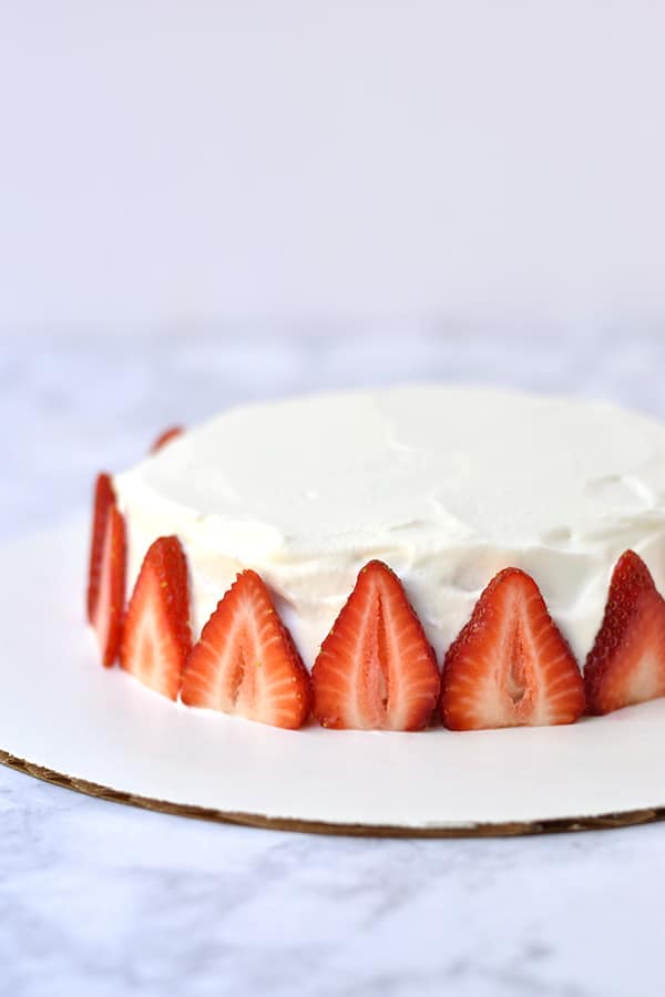 Side view of Japanese strawberry shortcake with strawberry slices around the perimeter. 