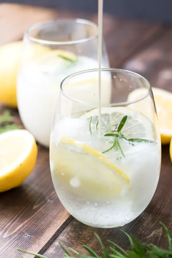 Pouring the rosemary lemon cream soda into a cup of rosemary lemon cream soda. 