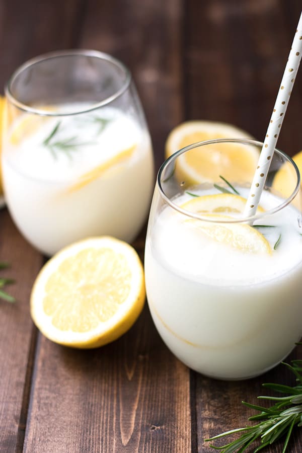 Two glasses of cream soda garnished with sliced lemons and fresh rosemary.