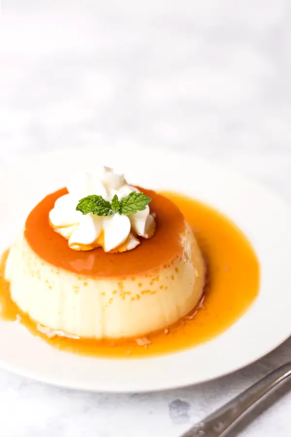 Purin, or Japanese custard pudding, with caramel sauce, topped with whipped cream and mint garnish.