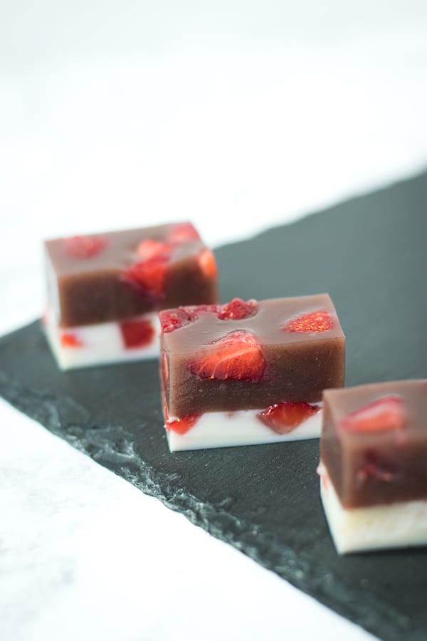 Strawberry and Milk Yokan cut into rectangles and lined up on black slate.
