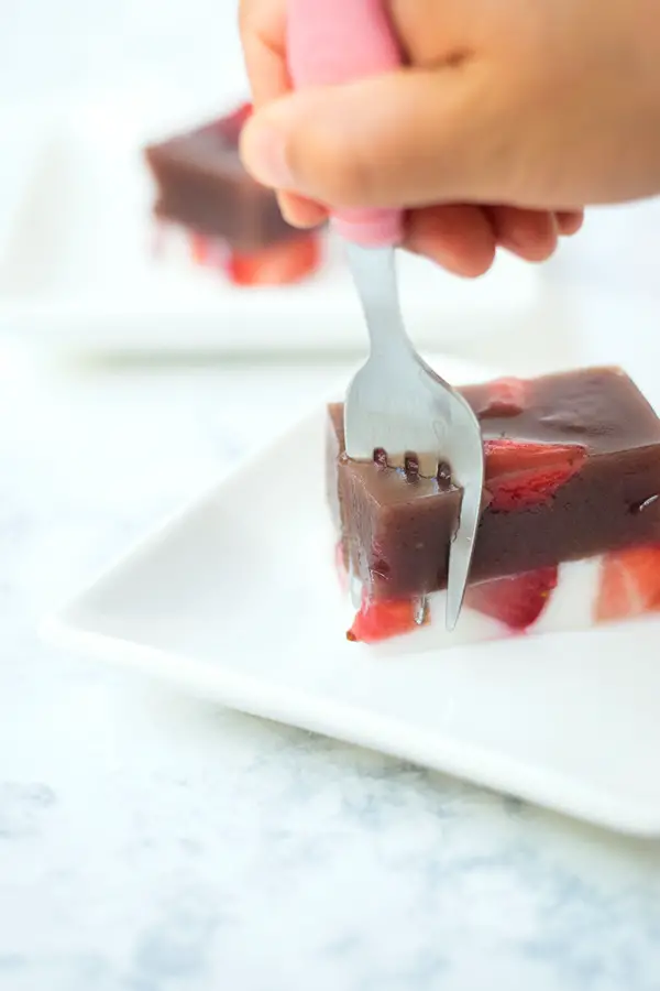 Fork cutting into strawberries and milk yokan. 