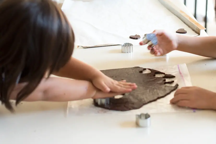 Kids cutting out cookies from dough using mini cookie cutters. 