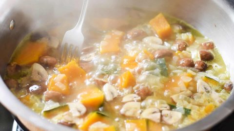 Recipe simmering in a pot. Testing the kabocha for firmness by piercing with a fork.