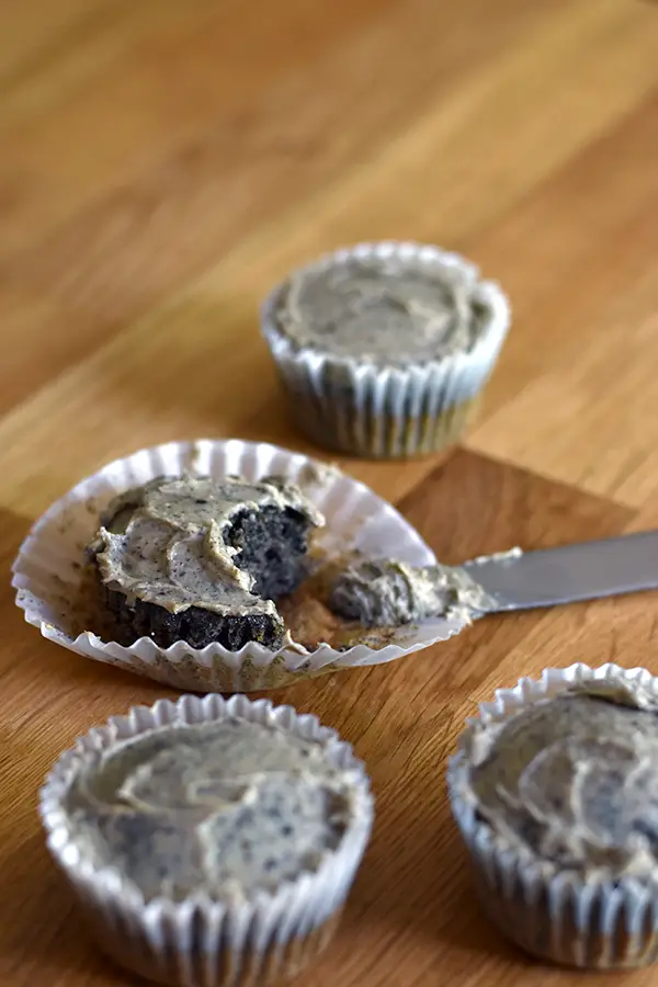 Black sesame cupcakes with peanut butter frosting with one cupcake with a bite taken out of it.