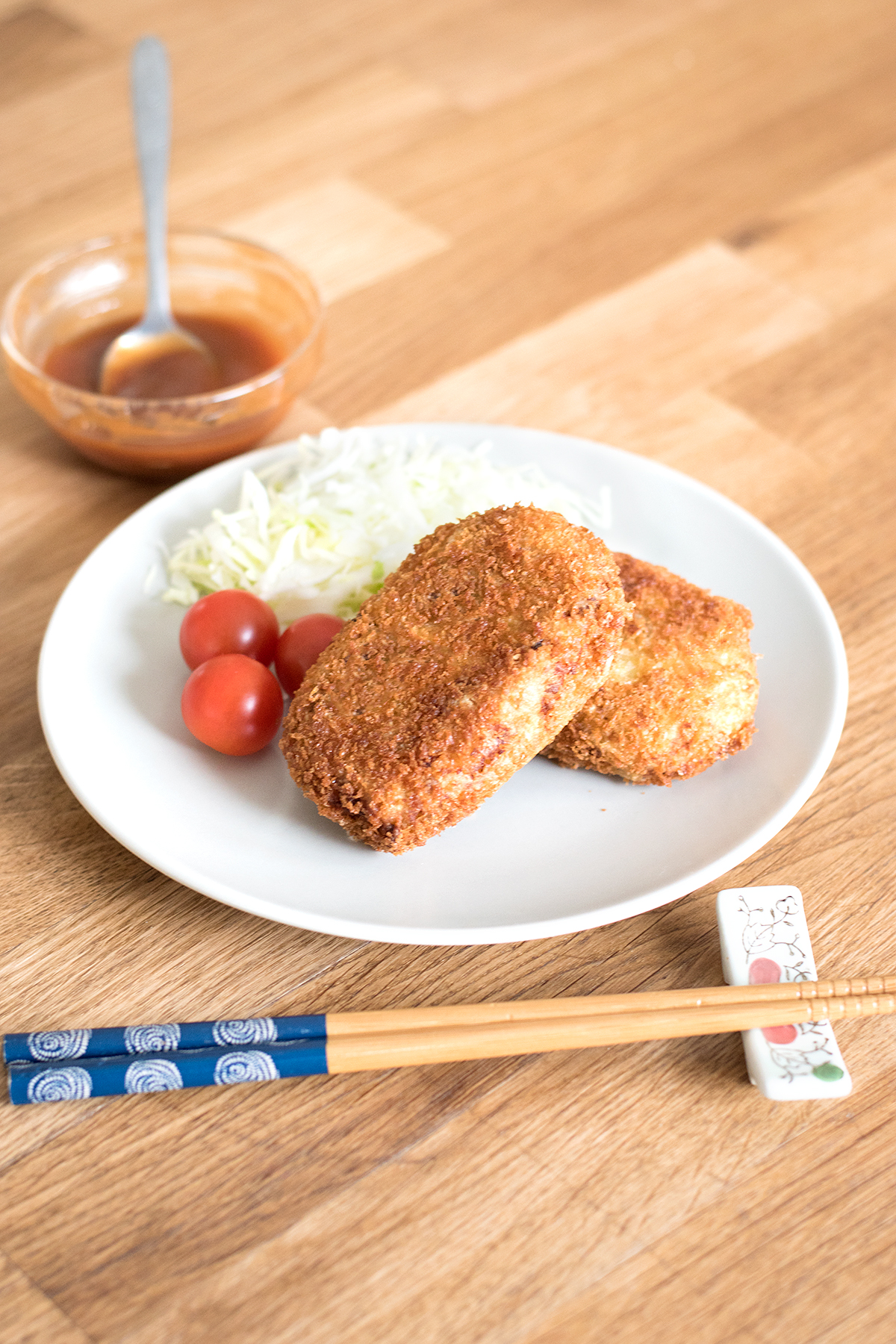 Finished picture of korokke dish (Japanese potato croquettes) with tonkatsu sauce in the background.