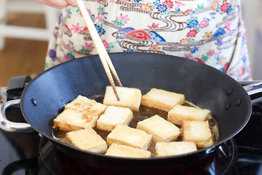 Coating the pan fried tofu in soy sauce glaze. 