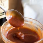 Spooning out some tonkatsu sauce out of a bowl, with worcestershire sauce bottle in the background.