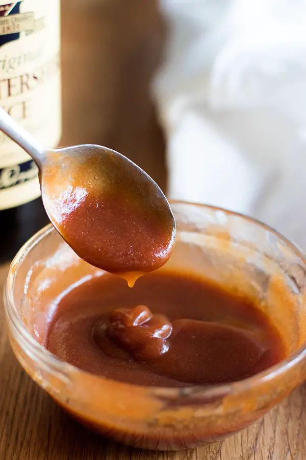 This tonkatsu sauce is easy to throw together and is tangy, rich, and perfect for dipping your favorite fried food! Spooning out some tonkatsu sauce out of a bowl, with worcestershire sauce bottle in the background.