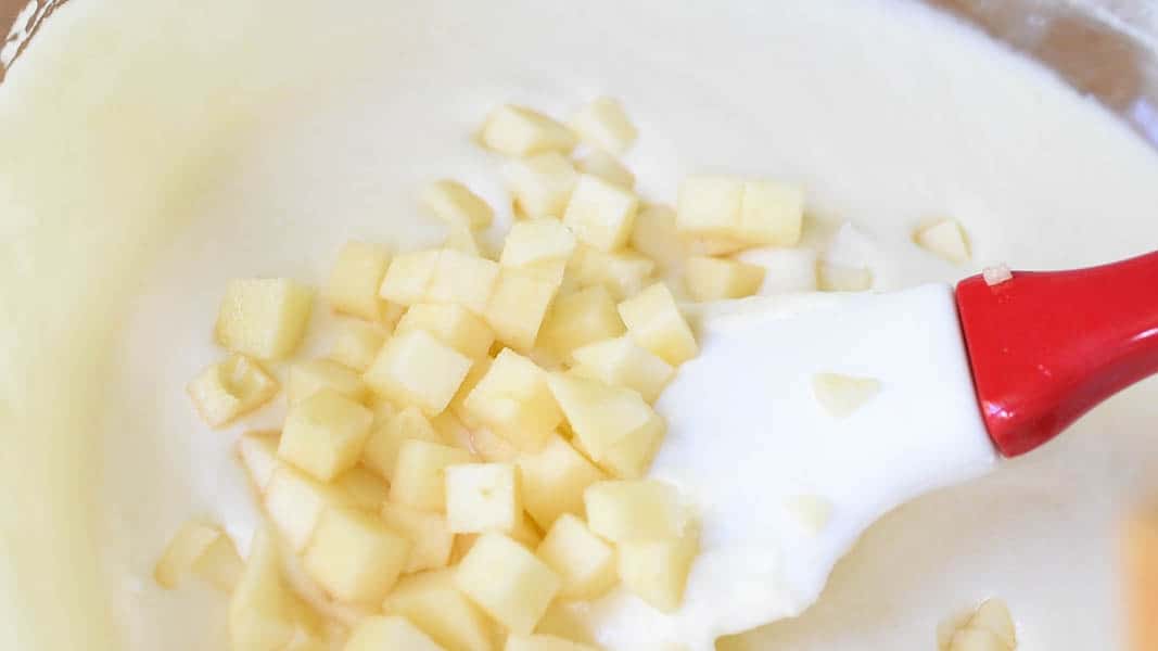 Folding diced apples into the apple compote and cream mixture.